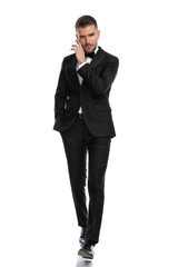 businessman walking towards the camera while touching his face