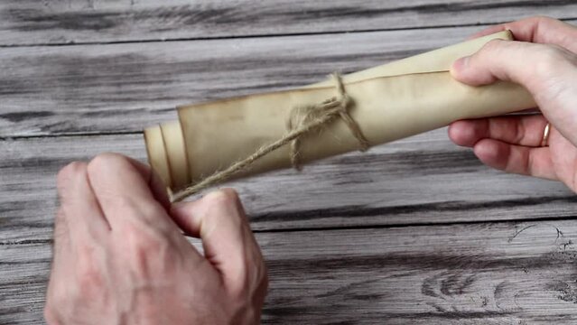 The Man Opens The Scroll. The Hand of Men Unfolds the Old Antique Scroll. The inside of the scroll is blank.