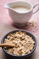 In the foreground, bowl with wholemeal oats for breakfast. in the background, pitcher with organic oat vegetable drink.