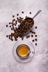 on the textured background, roasted coffee beans and a glass cup with Italian espresso. Copy space.