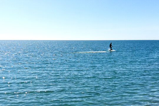 Man surfing on hydrofoils. Silhouette on the background of the sea surface on a bright sunny day