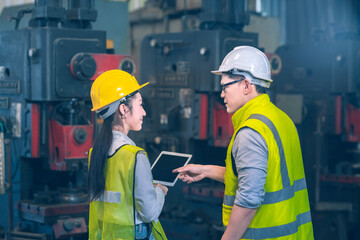 The chief engineer safty white helmet advice something to the newbie engineer  yellow safety helmet on the tablet and fix the machine in front of them