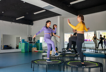 Four young women on trampoline, young fitness girls trains on   fitness studio.