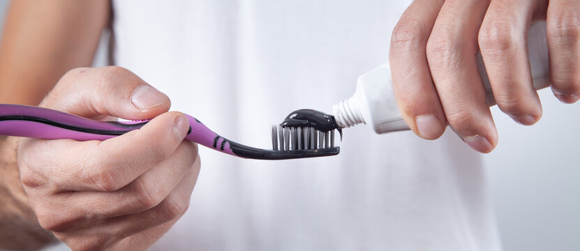 Man Holding Black Toothpaste And Toothbrush.