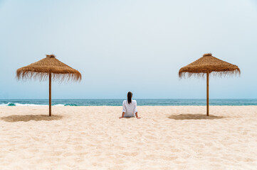 Female traveler sitting on sand near ocean