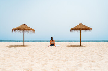 Fototapeta na wymiar Female traveler sitting on sand near ocean