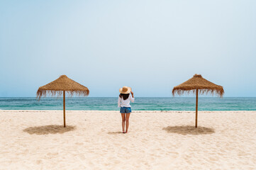 Female traveler standing on sand near ocean