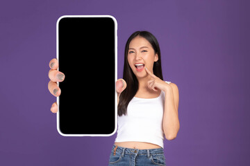 Beautiful Asian brunette woman cute girl in white tank top ,Excited surprised girl showing big smart phone with blank screen , white screen isolated purple background , Mock Up Image