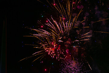 Beautiful festive fireworks, red-yellow, with haze, in the night sky