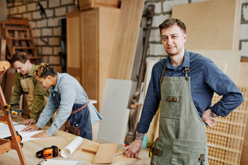 Warm toned portrait of smiling male carpenter looking at camera while standing casually in artisan workshop, copy space - obrazy, fototapety, plakaty