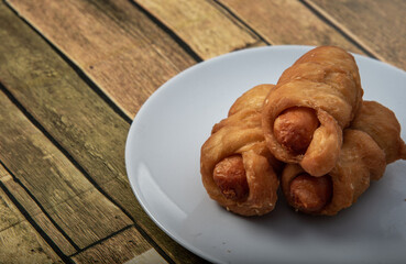 Asian street food sausage bread. On wooden floor, in white plate.