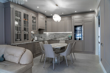 Fototapeta na wymiar Modern beige and grey colored kitchen interior in classic style with dining table in luxury home