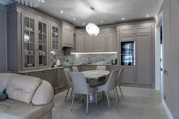 Modern beige and grey colored kitchen interior in classic style with dining table in luxury home
