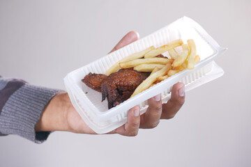 Crispy fried chicken wings and fries in a take away packet .