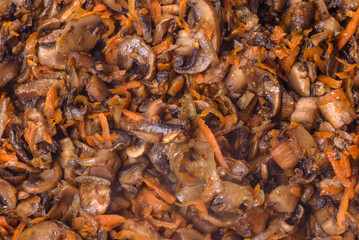 Fried champignons with carrots, onions and spices in a pan against a dark concrete background