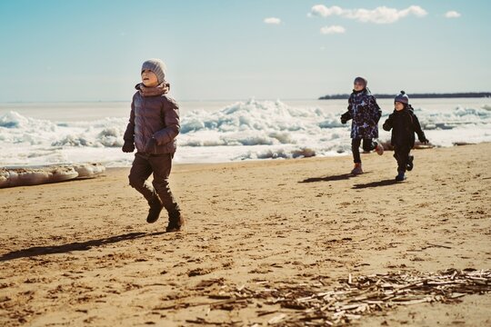 boys running along beach of finland gulf covered with ice. Image with selective focus