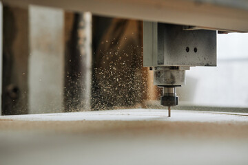 Macro shot of CNC engraving machine cutting wood in automated production workshop with sawdust...