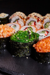 Close up of sliced sushi roll with seaweed, shrimp and sprinkled with sesame seeds.