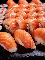 Philadelphia sushi with avocado, cream cheese, salmon and masago caviar on a black slate.