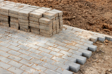 Pavement repair and laying of paving slabs on the walkway, stacked tile cubes on the background. Laying paving slabs in the pedestrian zone of the city, sand filling. Road tiles and curbs.