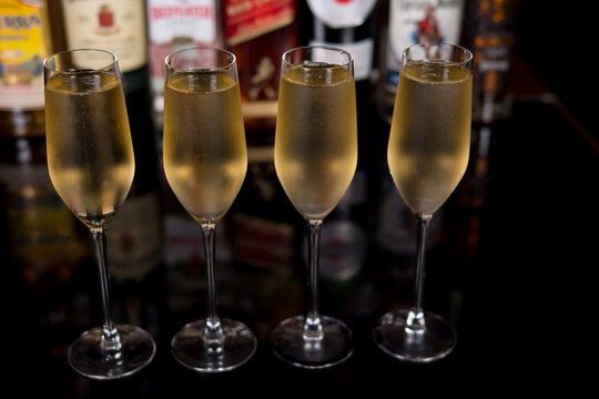 Close-up of a row of champagne glasses in a bar against the background of blurred bottles with various alcohol. The concept of alcohol and holidays.
