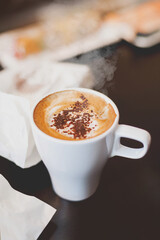 White cup of coffee with cinnamon. Hot tasty cappuccino and snacks on wooden table. Coffeebreak of lunch in cafe.