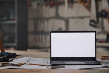 Close up background image of opened laptop with blank white screen on table in workshop, copy space