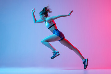 Fototapeta na wymiar Studio shot of professional female athlete, runner training isolated on pink studio background with blue neon filter, light. Concept of action, motion, speed