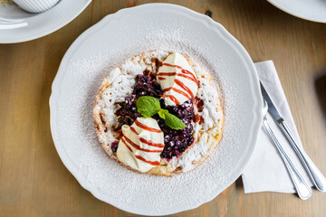 pancake with whipped cream and blueberries sprinkled with powdered sugar