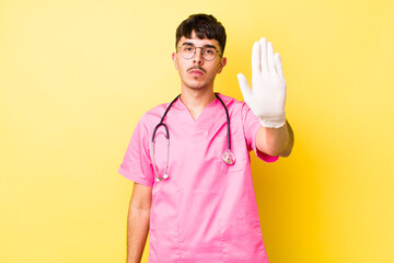 young hispanic man looking serious showing open palm making stop gesture. veterinarian concept