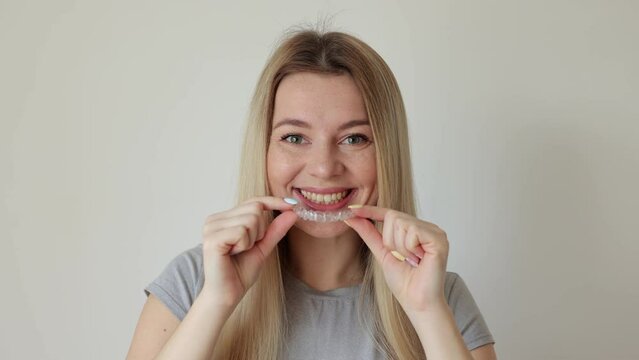 Woman using clear removable braces, invisible teeth tray.
