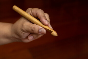 Close-up of a crochet needle made of bamboo material next to a ball of green wool. Concept of leisure and free time
