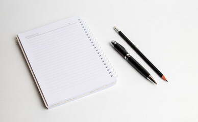 blank notebook with pen and pencil on white background, business concept
