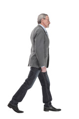 side view full length photo of a mid aged business man walking forward and looking at camera.