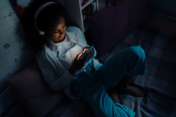 African teen girl with phone listening music and watching video
