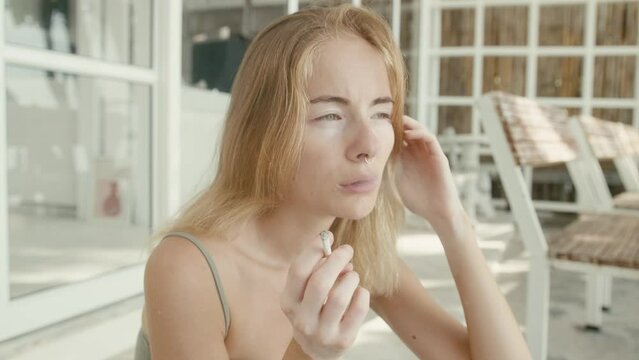 Pretty young woman with vitiligo pigmentation sits on the stairs and smokes 
