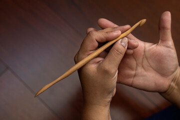 Closeup of a woman's hands holding a bamboo crochet needle. Concept of leisure and free time