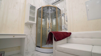 Bathroom with shower and sofa. Action. Beautiful interior of expensive bathroom with shower and sofa for relaxing. Expensive stylish bathroom with shower