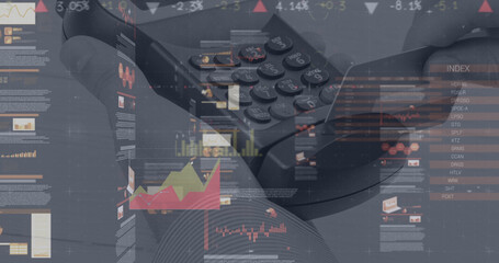Image of graphs and financial data over hand of caucasian man holding payment terminal