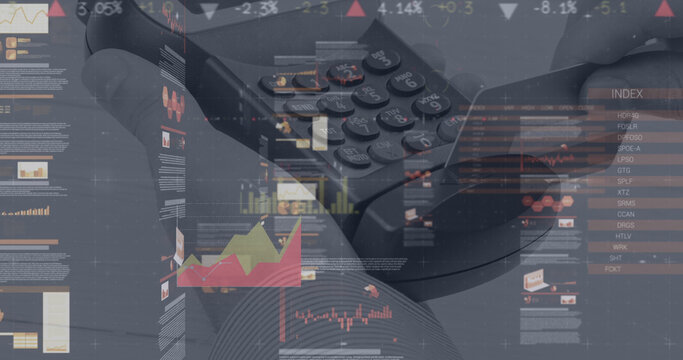 Image of graphs and financial data over hand of caucasian man holding payment terminal