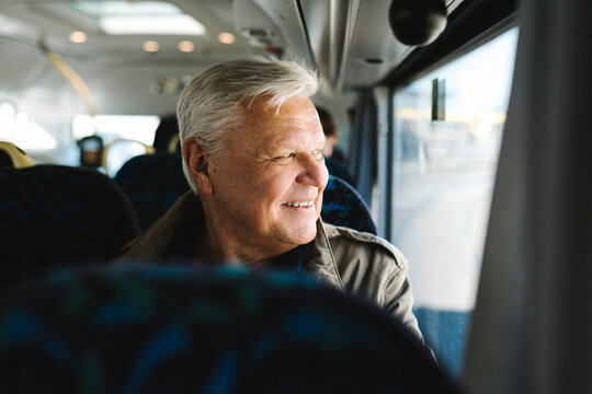 Happy businessman with gray hair looking through bus window