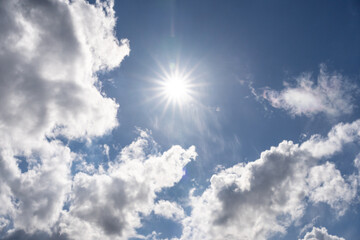 Bright sun on a summer afternoon with light light white clouds and blue sky