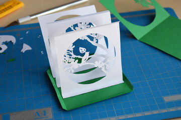 Making  tunnelbook. 3D greeting card "Spring". Artwork equipment and tools for paper cut - cutting knife, sharp box cutter, blue cutting plate, origami paper. Modern 3d origami paper art style.