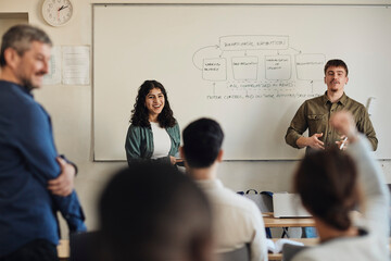 Male and female students interacting with friends during Q and A session in classroom