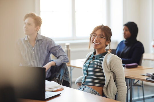 Portrait of smiling young female student sitting in classroom