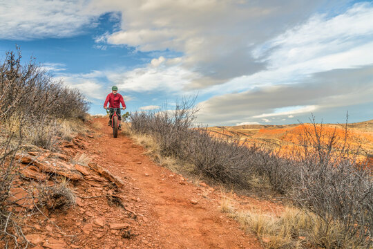 a senior male riding a fat mountain bike on a single track trail in Red Mountain Open Space in Colorado, late fall scenery
