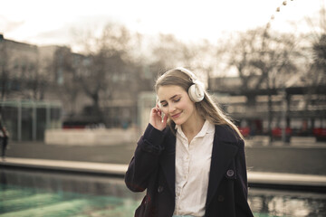 young woman listens to music in the street