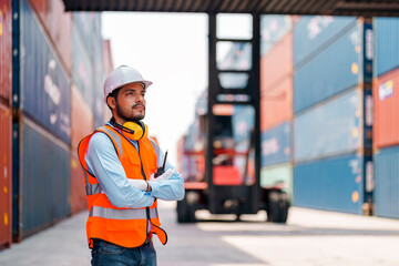 Asian worker with cross arms holding walkie talkie at container yard.