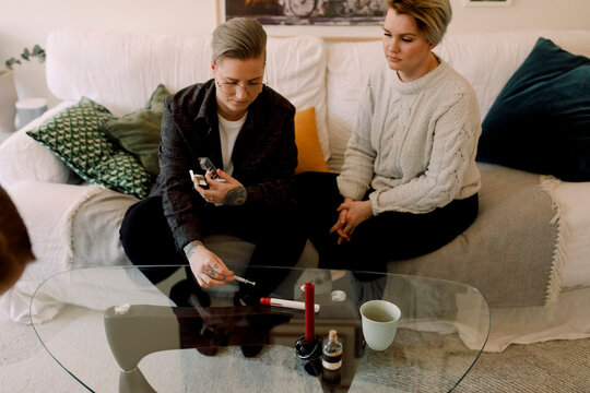 Lesbian Couple With IVF Kit Sitting On Sofa At Home