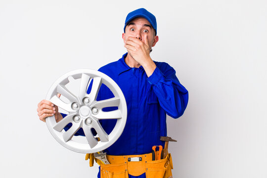 hispanic man covering mouth with hands with a shocked. car mechanic concept